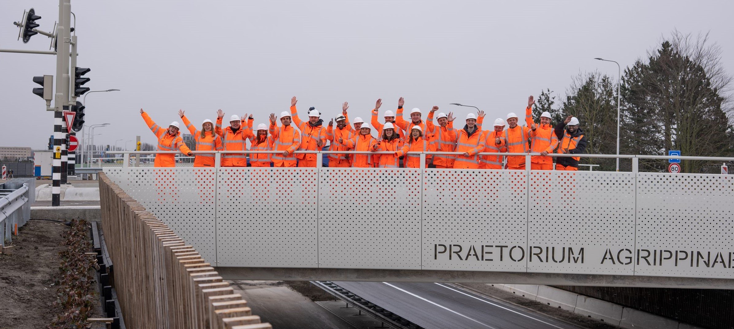 SWARCO collega's zwaaien vanaf een project brug naar de camera
